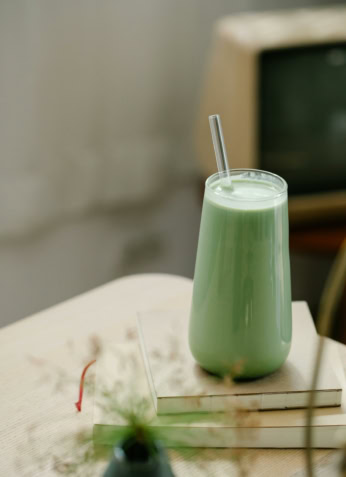 Smoothie vert healthy avec paille, sur table en bois, style minimaliste, ambiance naturelle, promotion nutrition saine, concept de bien-être.