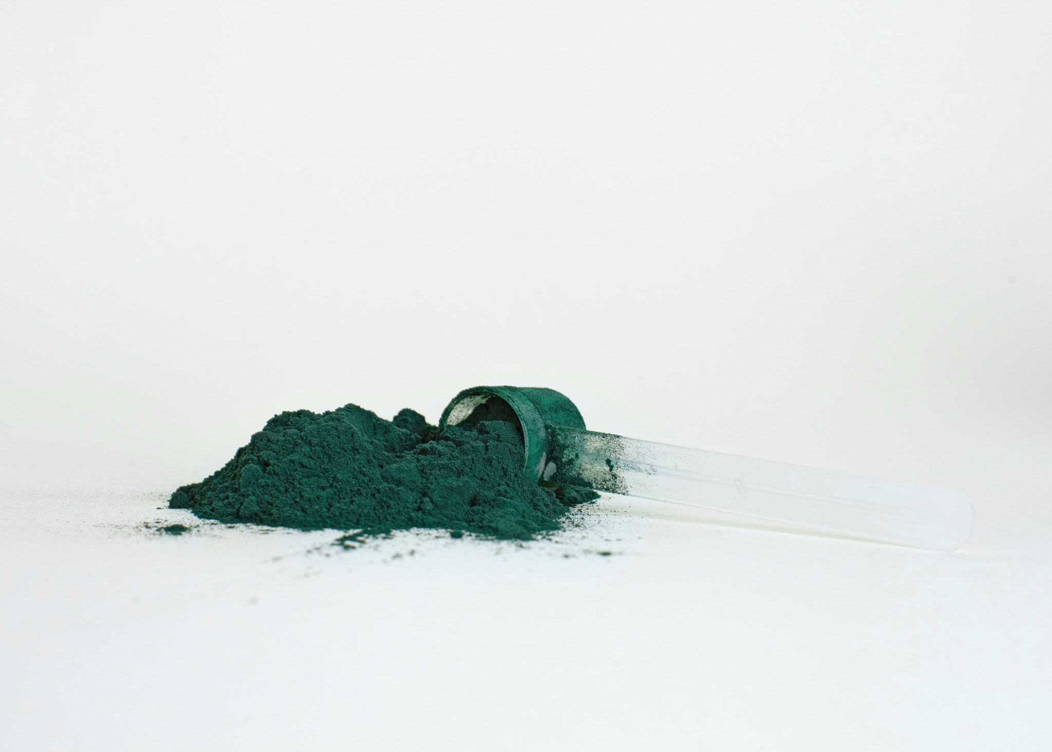 Poudre verte en supplément nutritionnel avec pipette, complément alimentaire sain et naturel, originellement conçu pour la santé et la vitalité, sur fond blanc épuré.