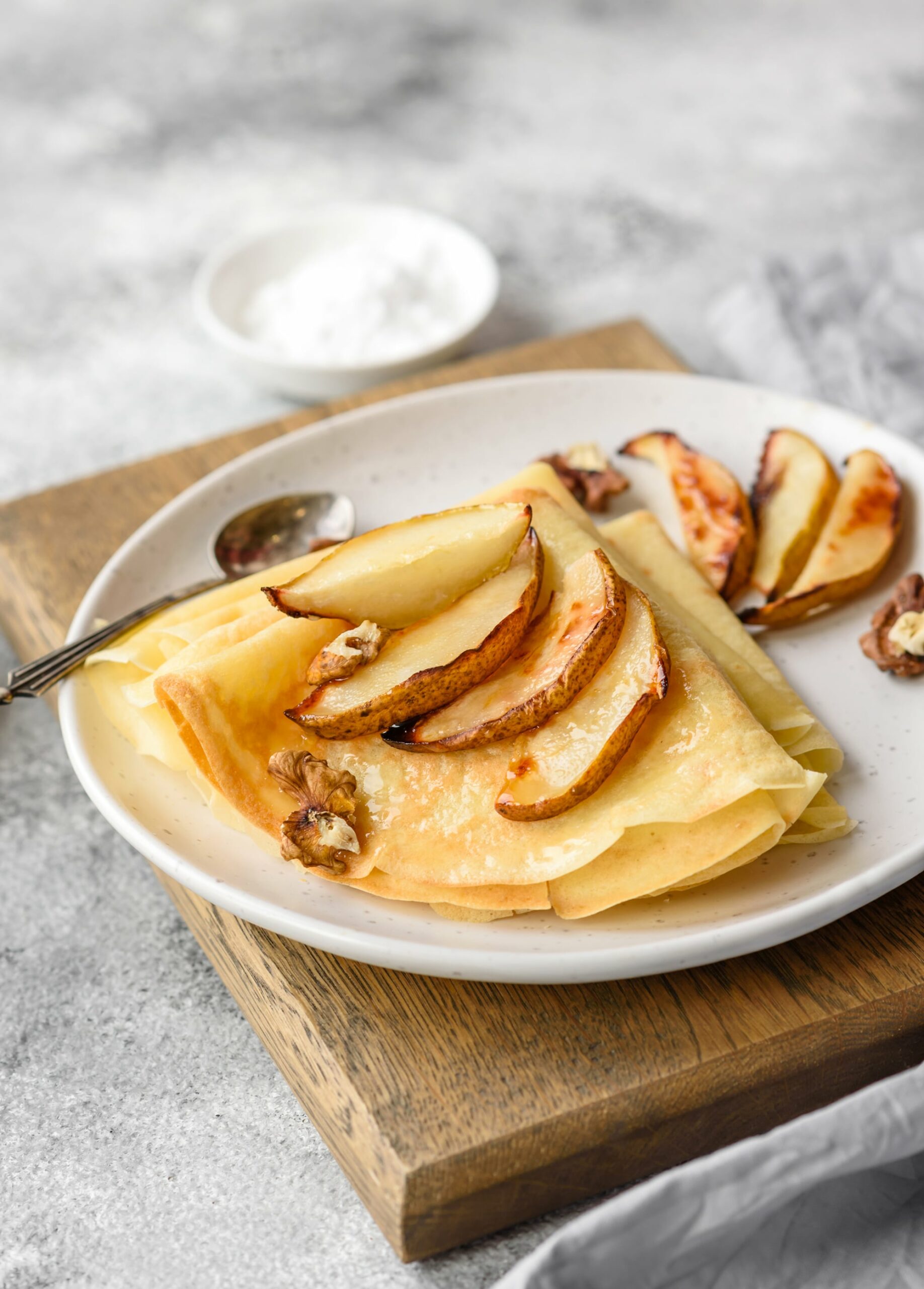 Croustade de poires et noix sur une assiette blanche, environnement naturel avec éléments de cuisine rustique, mise en valeur d'une pâtisserie saine et gourmande, parfaite pour une alimentation équilibrée.
