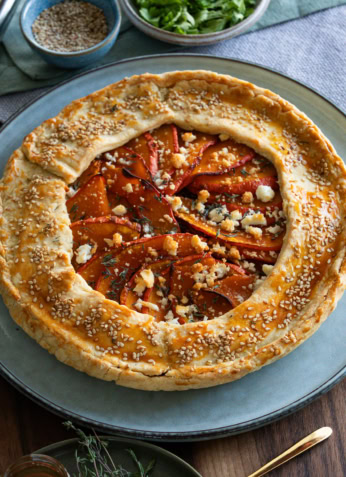 Galette rustique aux légumes, pâte feuilletée, poivrons et fromage, décorée de sesame et herbes fraîches, accompagnée de salade verte, dans une cuisine conviviale, cuisine saine et gourmande.