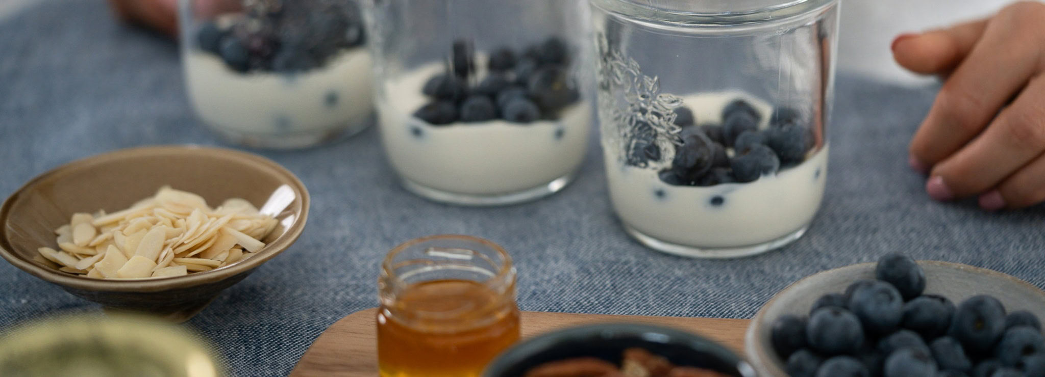 Fraises, myrtilles et amandes enrobées de yaourt nature dans des verrines, avec granola et miel, illustrant alimentation saine et équilibre alimentaire pour le bien-être.