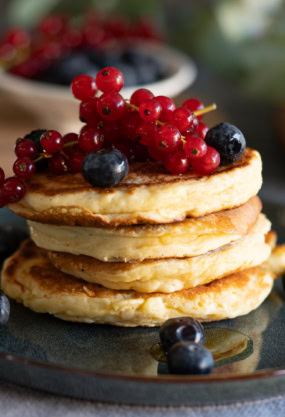 Délicieux pancakes aux fruits rouges frais et myrtilles, parfaits pour une alimentation saine et équilibrée, idéal pour un petit déjeuner nutritif.