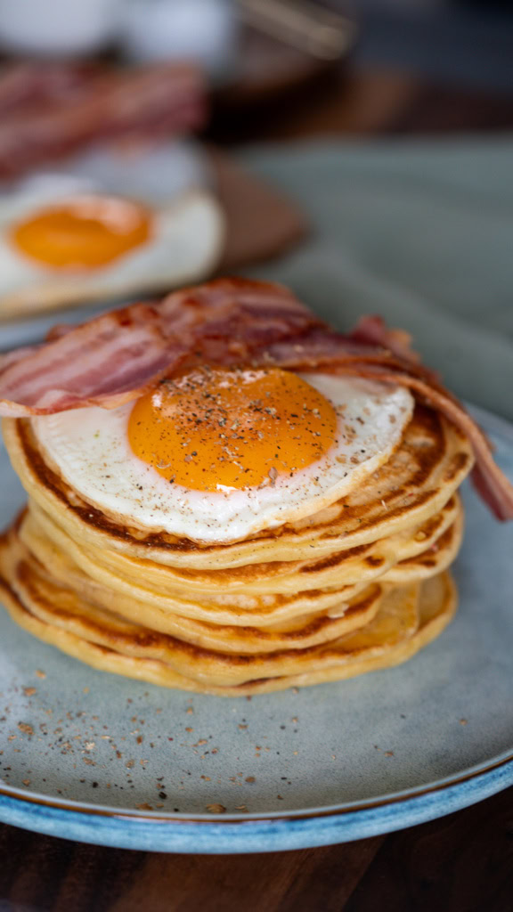 Oeufs au plat sur pancakes, avec bacon, petits déjeuners riches en protéines et saveurs gourmandes, idéale pour un petit déjeuner équilibré.