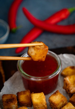 Fritures de tofu croustillant avec sauce tomate, accompagnées de piments rouges frais, mettant en valeur une alimentation saine et savoureuse pour une nutrition équilibrée.