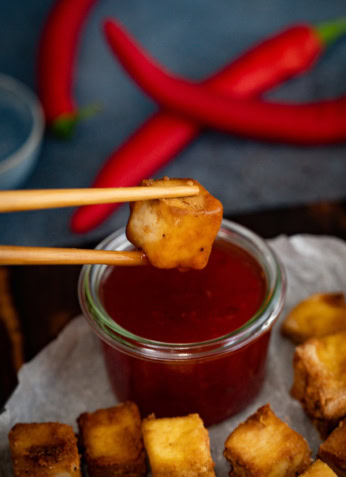 Fritures de tofu croustillant avec sauce tomate, accompagnées de piments rouges frais, mettant en valeur une alimentation saine et savoureuse pour une nutrition équilibrée.