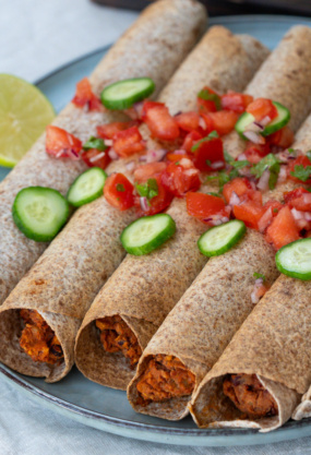 Poulet tikka masala dans des wraps de blé complet garnis de légumes frais, servi avec une tranche de citron, idéal pour une alimentation équilibrée et gourmande - Noémie Nutrition, expert en nutrition saine.