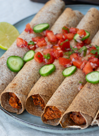 Poulet tikka masala dans des wraps de blé complet garnis de légumes frais, servi avec une tranche de citron, idéal pour une alimentation équilibrée et gourmande - Noémie Nutrition, expert en nutrition saine.